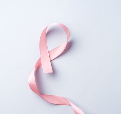 Breast cancer awareness pink ribbon symbol and letter board on gray background.